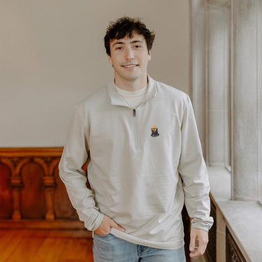Male model wearing the smoke-colored Alpha Epsilon Pi Embroidered Luxe Quarter Zip with crest embroidery, standing by a window in a formal setting.
