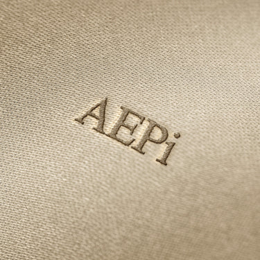 Soft beige fabric close-up showing a smooth, heavyweight knit texture with gentle folds and subtle draping.