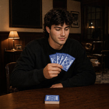 Fraternity brother holding custom Heritage Playing Cards during a poker game in a chapter house lounge.