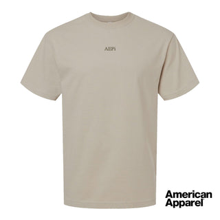 Beige short sleeve crewneck t-shirt with small embroidered text at the center chest on a clean background.